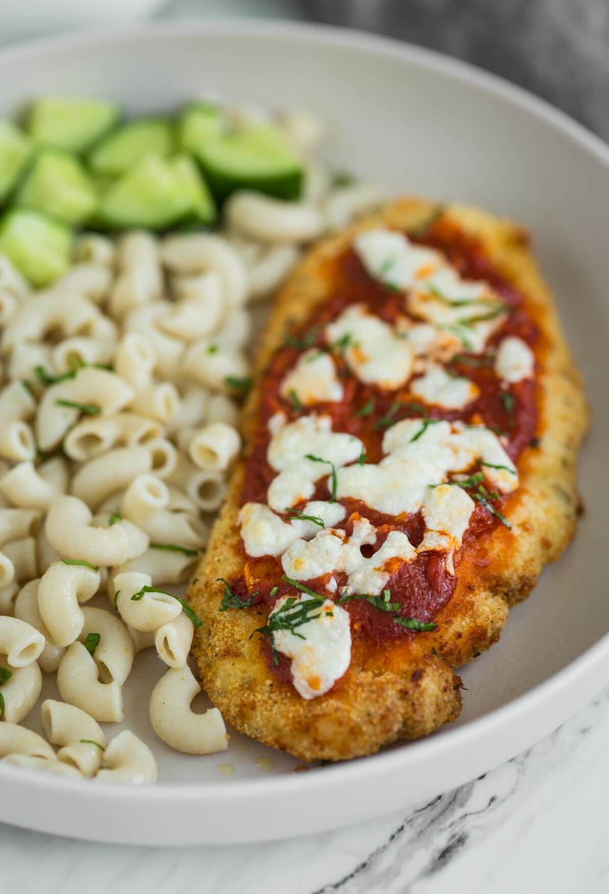 air fryer chicken parmesan in a serving plate with some plain macaroni pasta