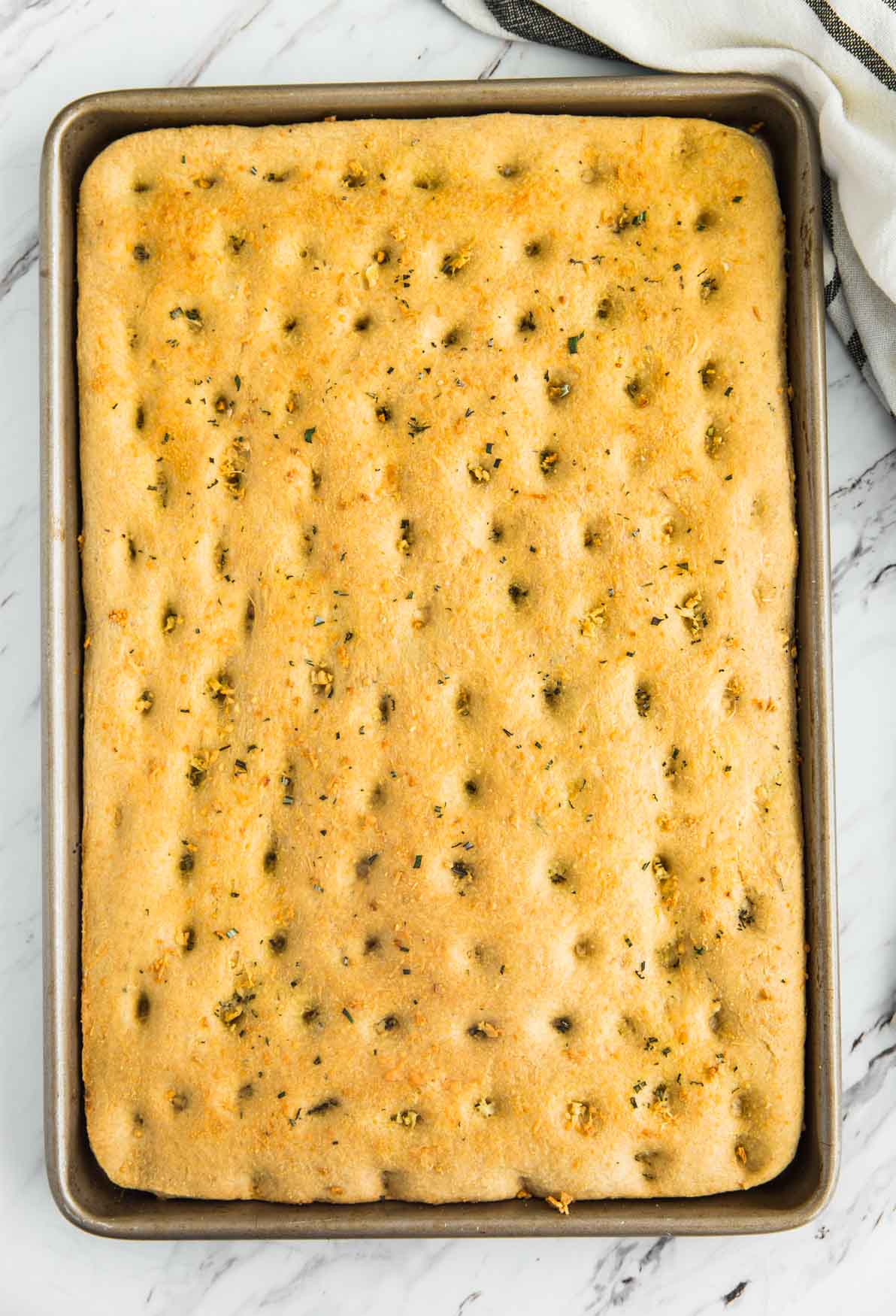 garlic herb whole wheat focaccia bread baked in a baking sheet pan