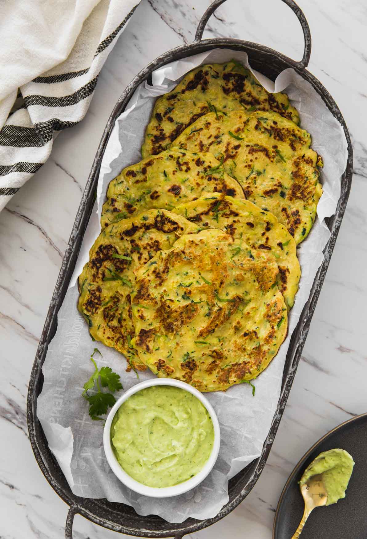 Zucchini pancakes with green sauce in a serving tray