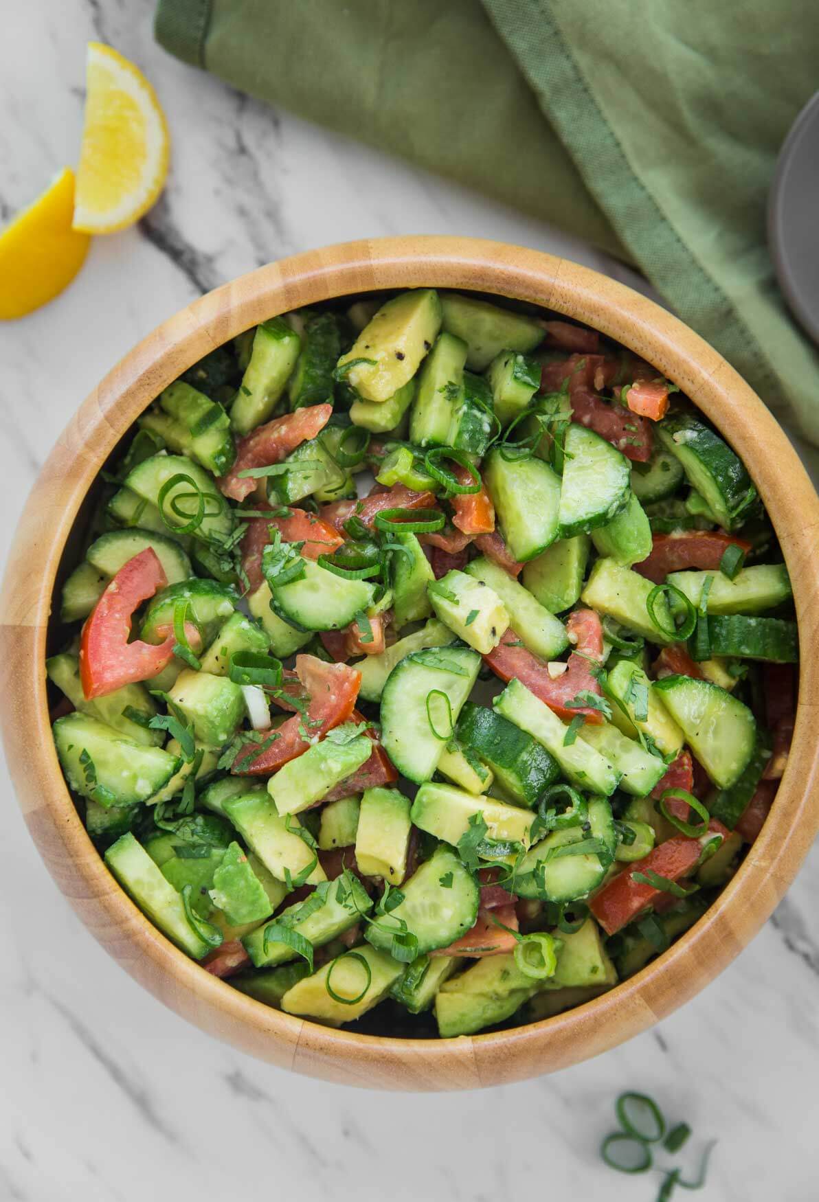 photo of avocado, cucumber and tomato salad in a large wooden salad bowl