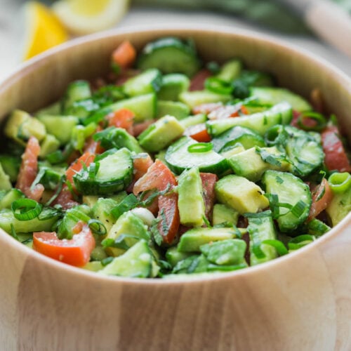 photo of avocado cucumber salad with tomato in a large wooden bowl