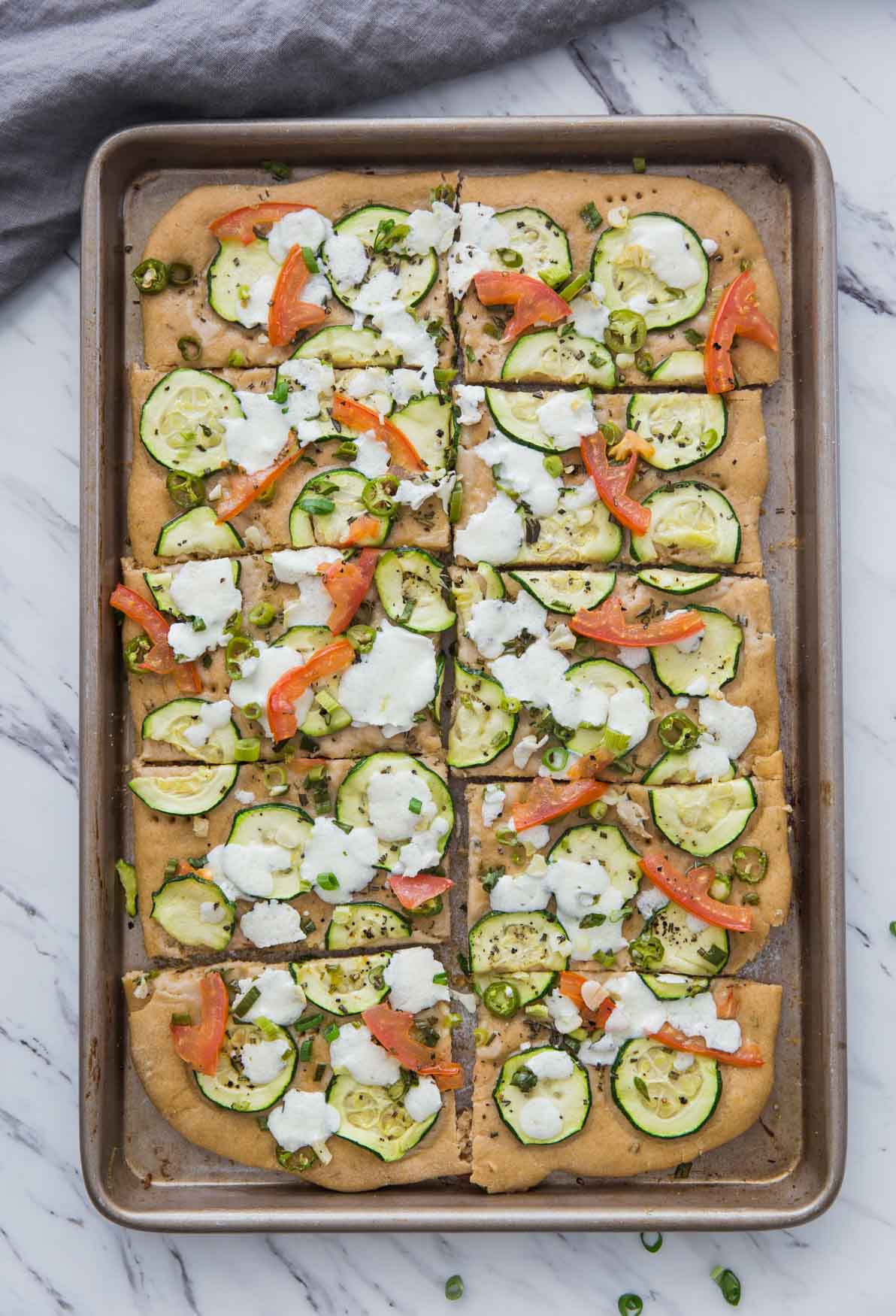 image of zucchini flatbread cut into slices in the baking tray.