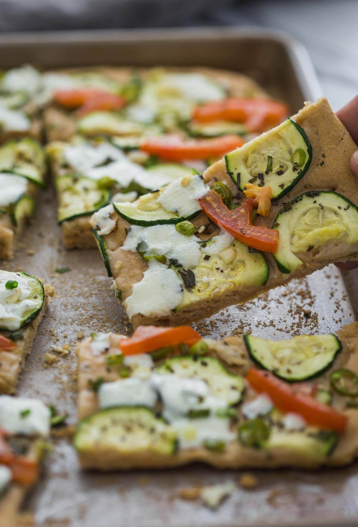 image of zucchini flatbread slice while lifting from the baking tray.