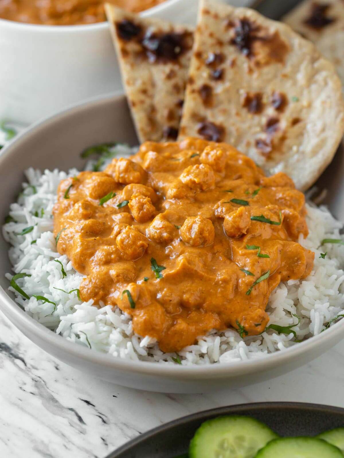 chickpea tikka masala in a serving deep plate with plain white rice and naan bread.