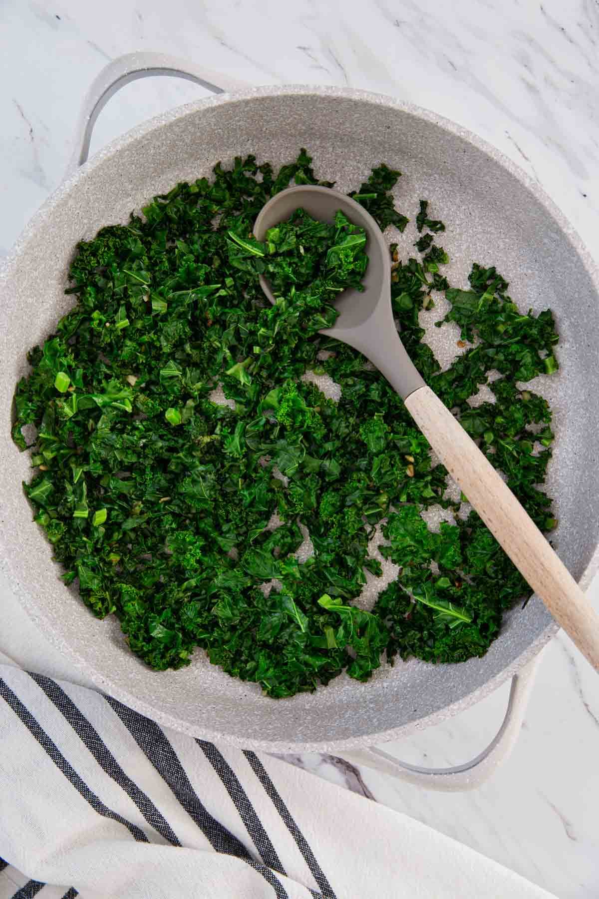 fresh kale sautéed in a large frying pan.