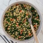 pesto kale pasta in a large frying pan with serving spoon.