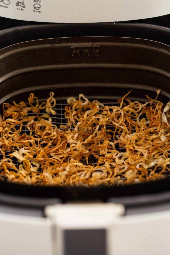 Air-fried crispy onions in the air fryer basket after the frying process is done.
