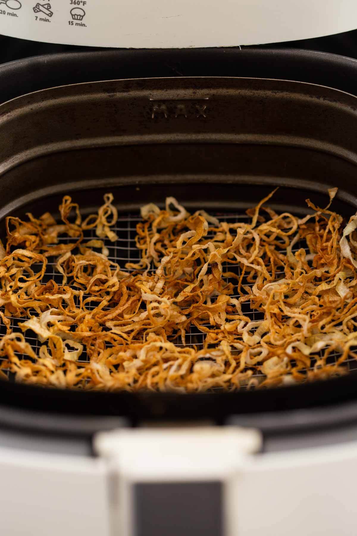 Air-fried crispy onions in the air fryer basket after the frying process is done.