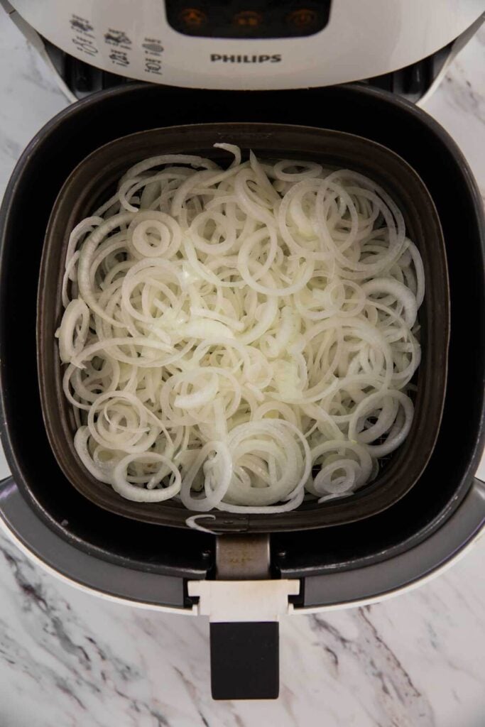 * Onion rings placed in the air fryer to prepare crispy air-fried onion strings.
