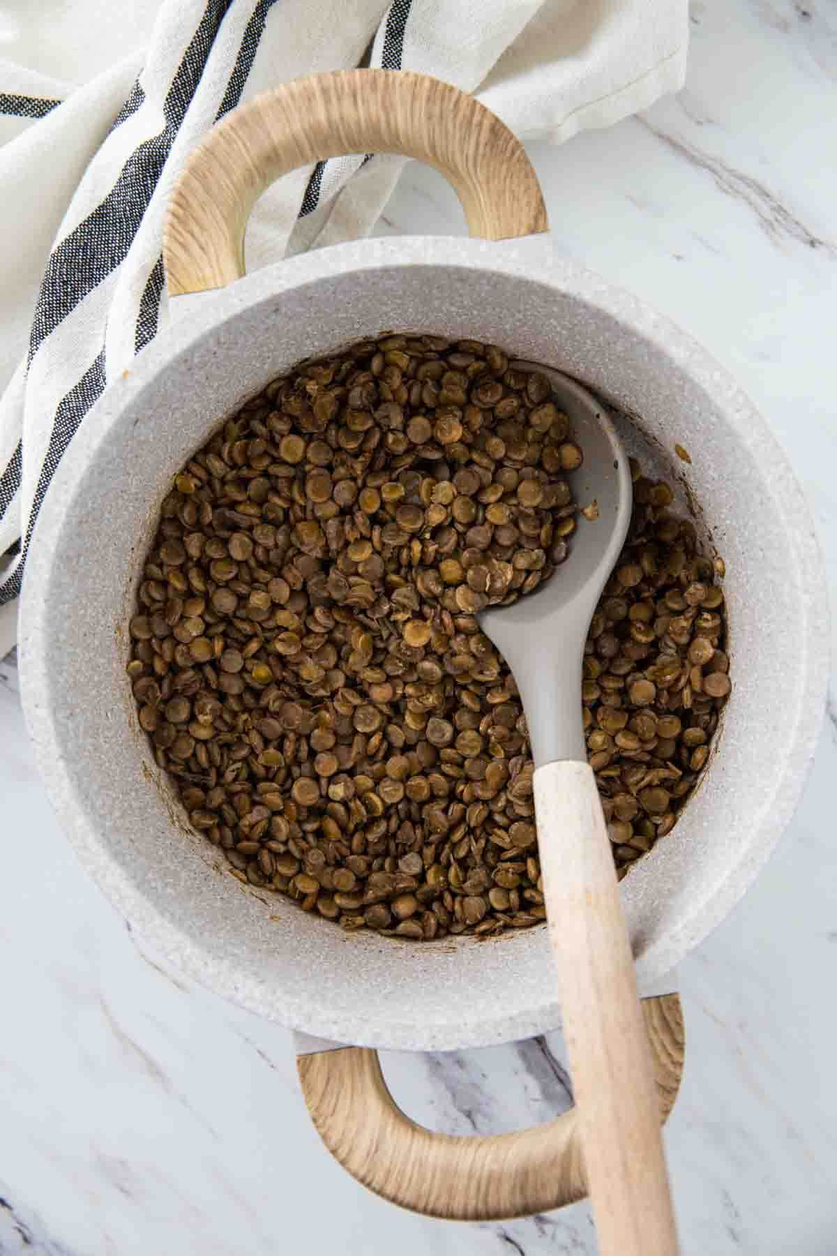 Cooked lentils in a pot with a serving spoon