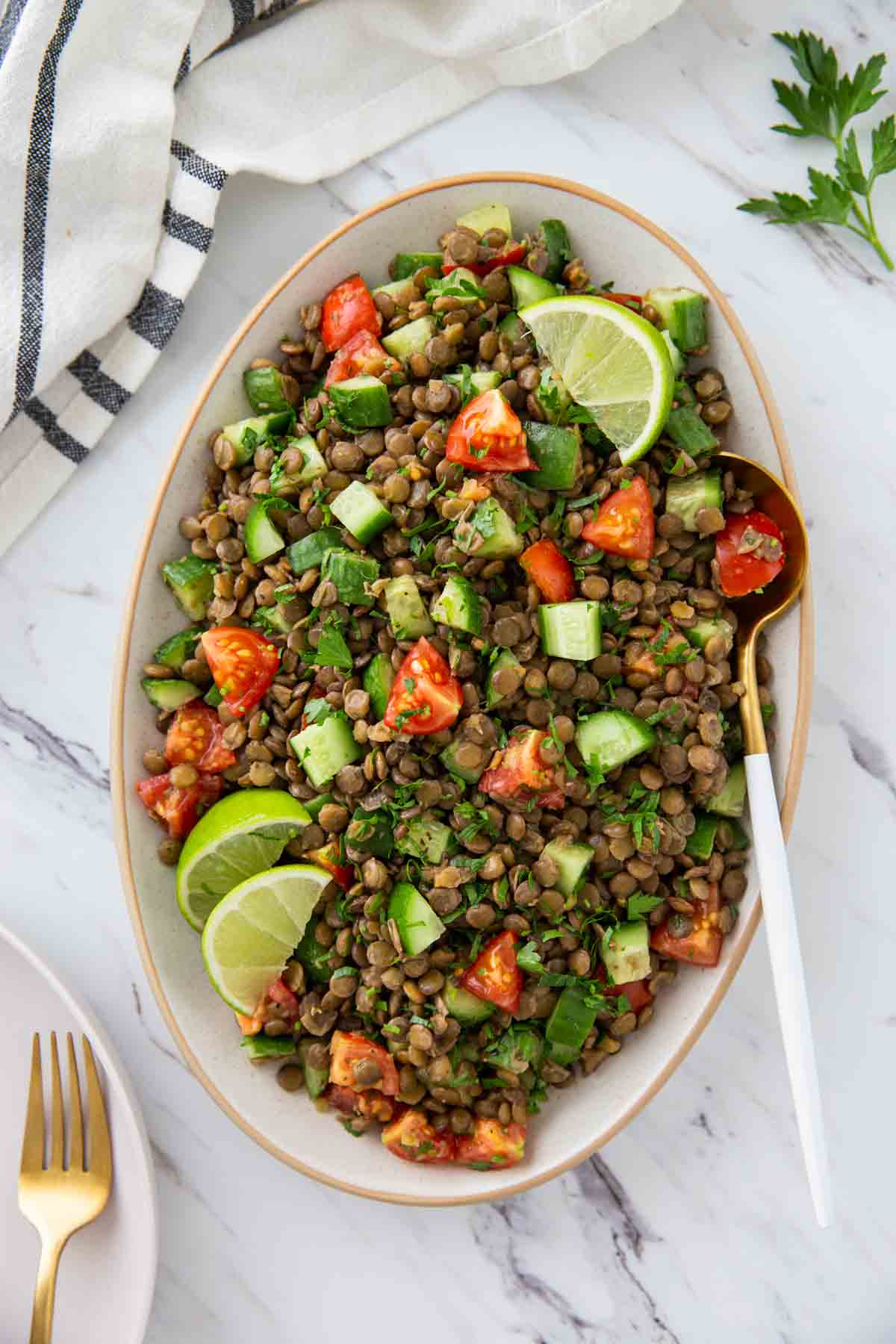 Prepared whole lentil salad in a serving dish with a serving spoon.