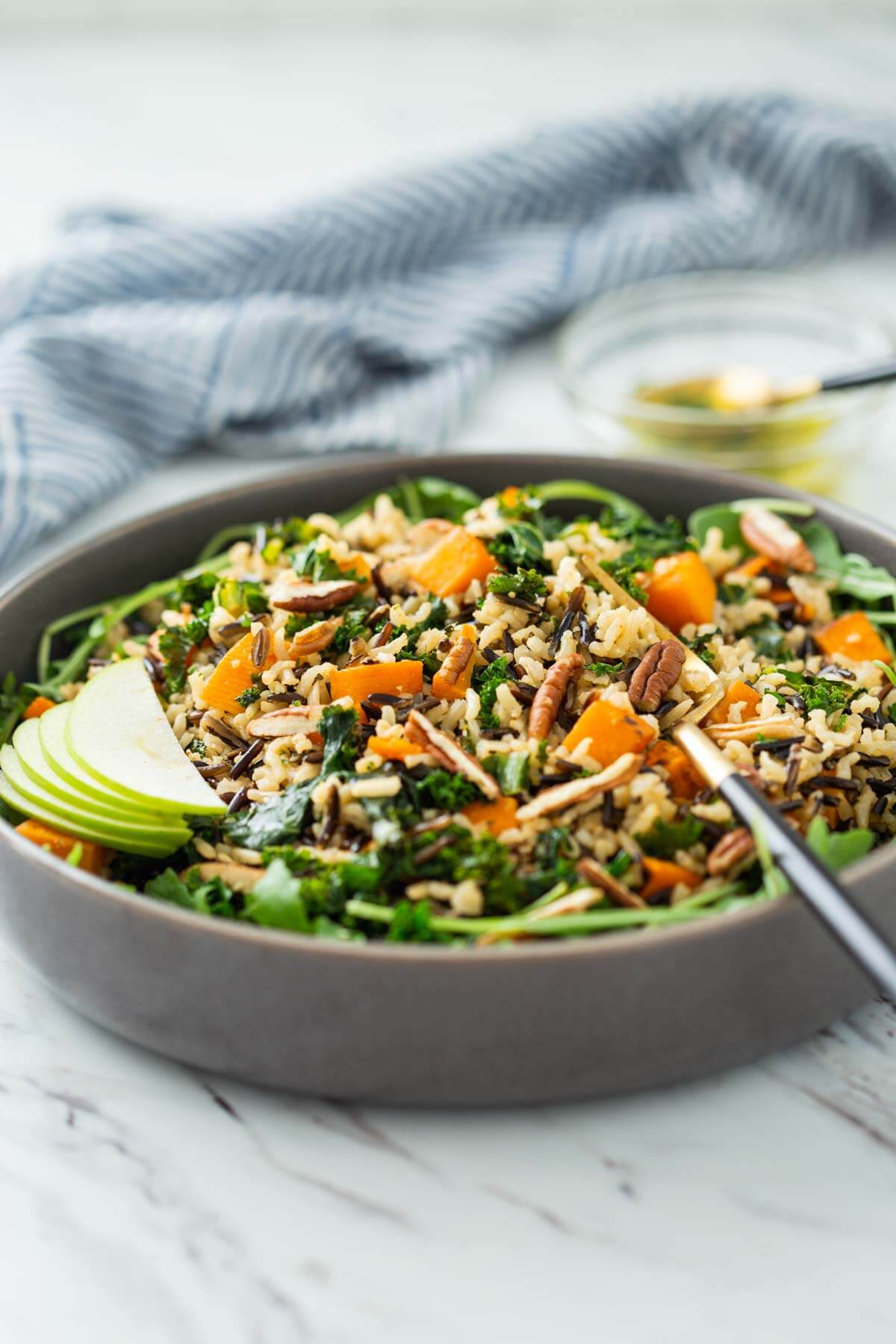 wild rice salad with sweet potato, kale and arugula in a serving bowl with serving fork.