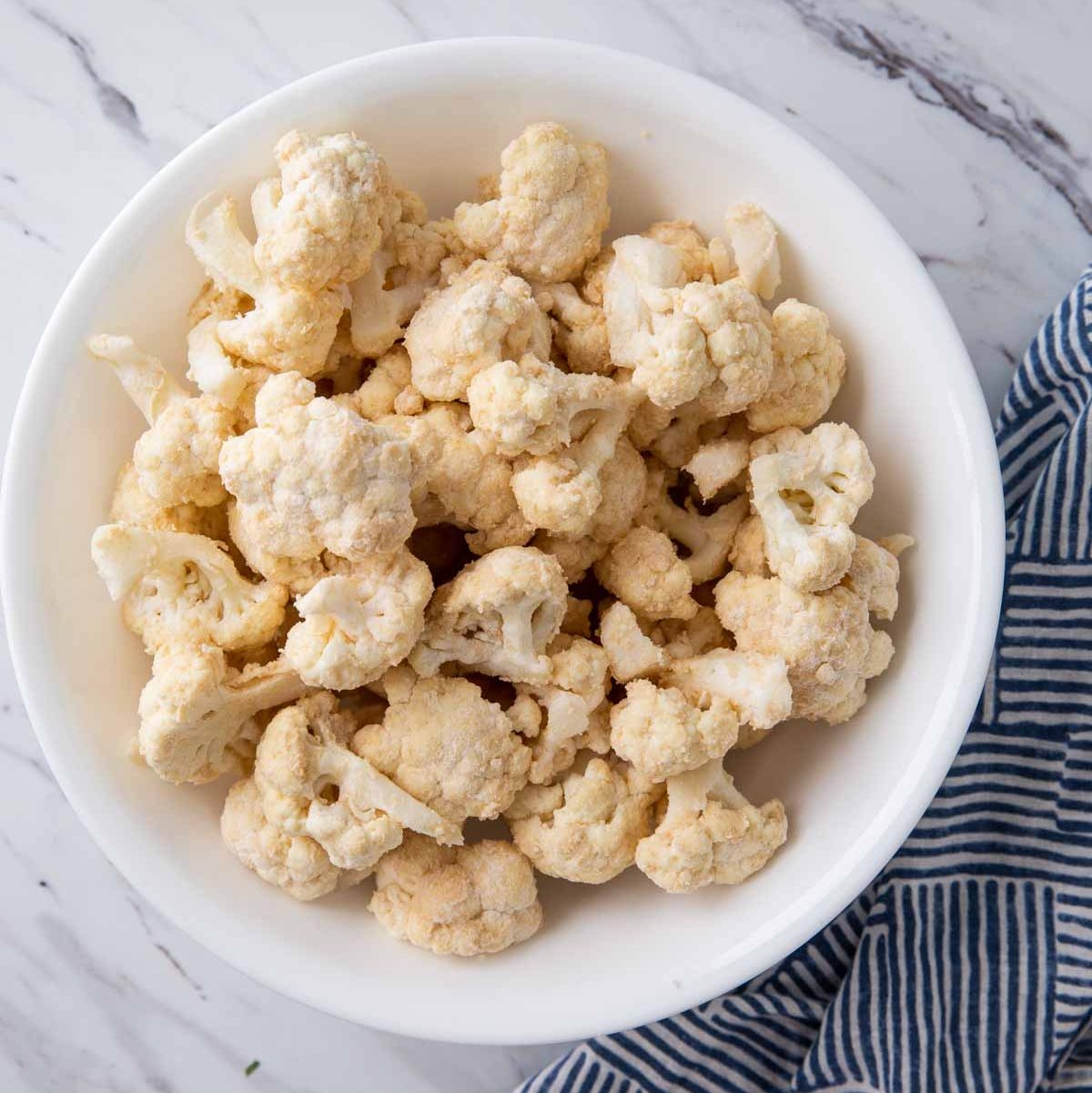 images of flour coated cauliflower florets in a mixing bowl