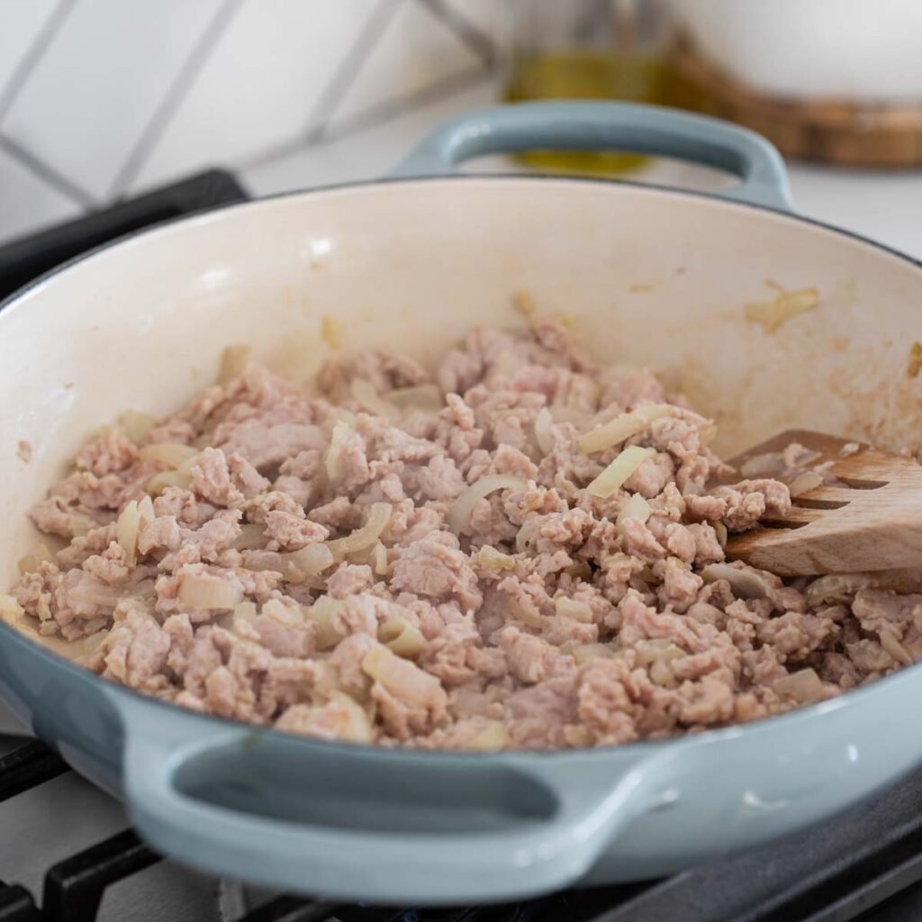 cooking ground chicken with onion in a large skillet.