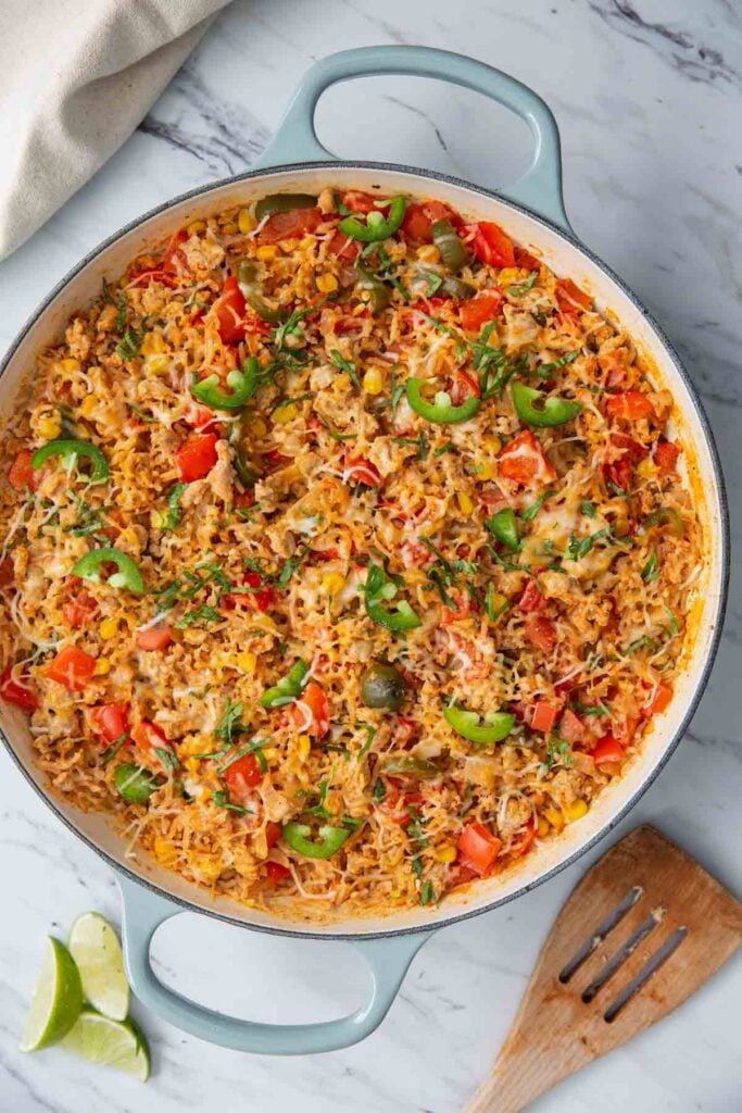taco rice casserole with ground chicken is prepared in a large cast iron skillet.