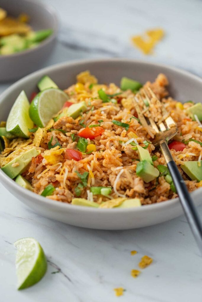Cheesy chicken taco rice in a serving dish with a serving spoon.