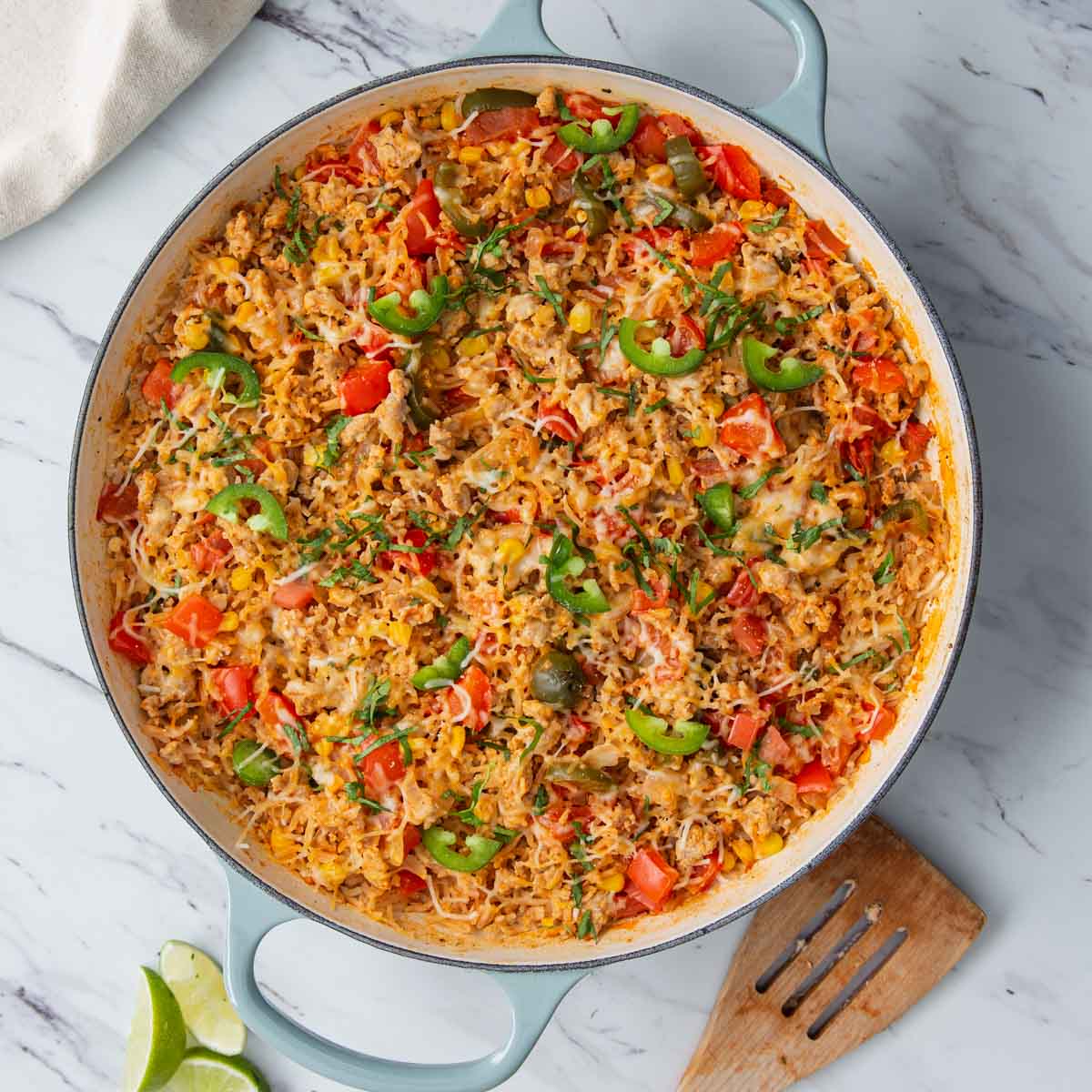 taco rice casserole with ground chicken is prepared in a large cast iron skillet.