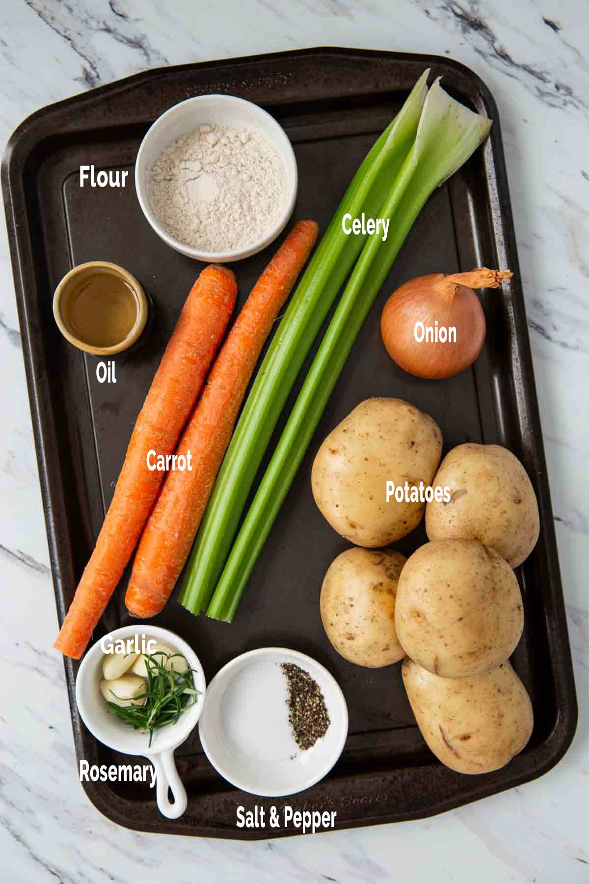 Raw ingredients for the making potato soup from scratch are gathered in a metal tray. 