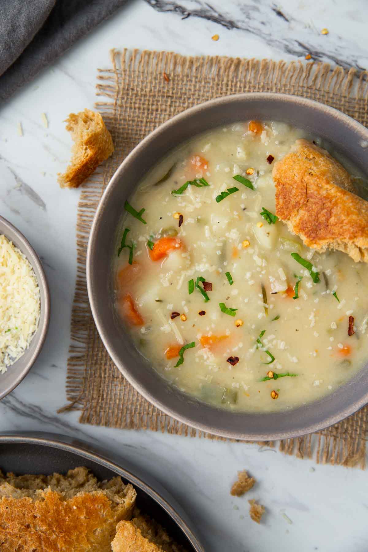 Creamy healthy potato soup with a piece of bread in a serving bowl.