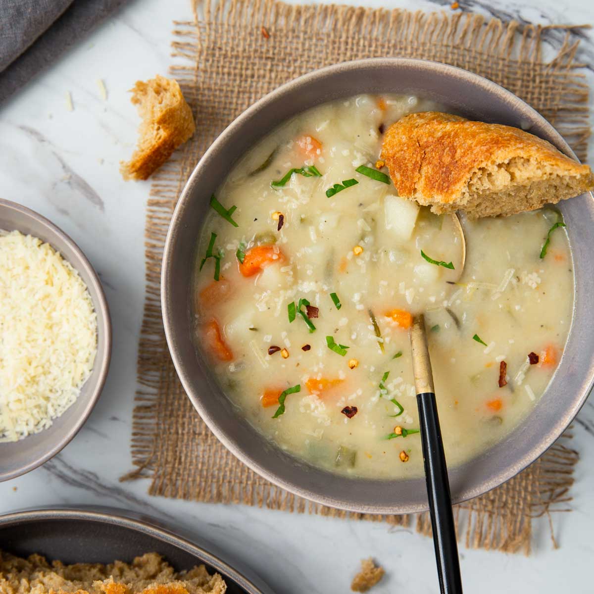 Creamy healthy potato soup with a piece of bread in a serving bowl.