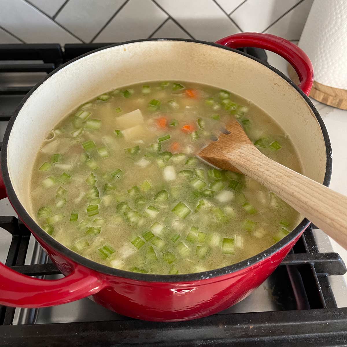 Potato soup mixture in a dutch oven on a gas stove.