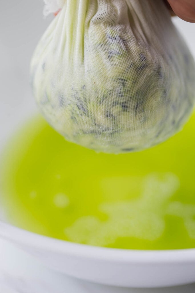 Process shot of squeezing water out of shredded zucchini.