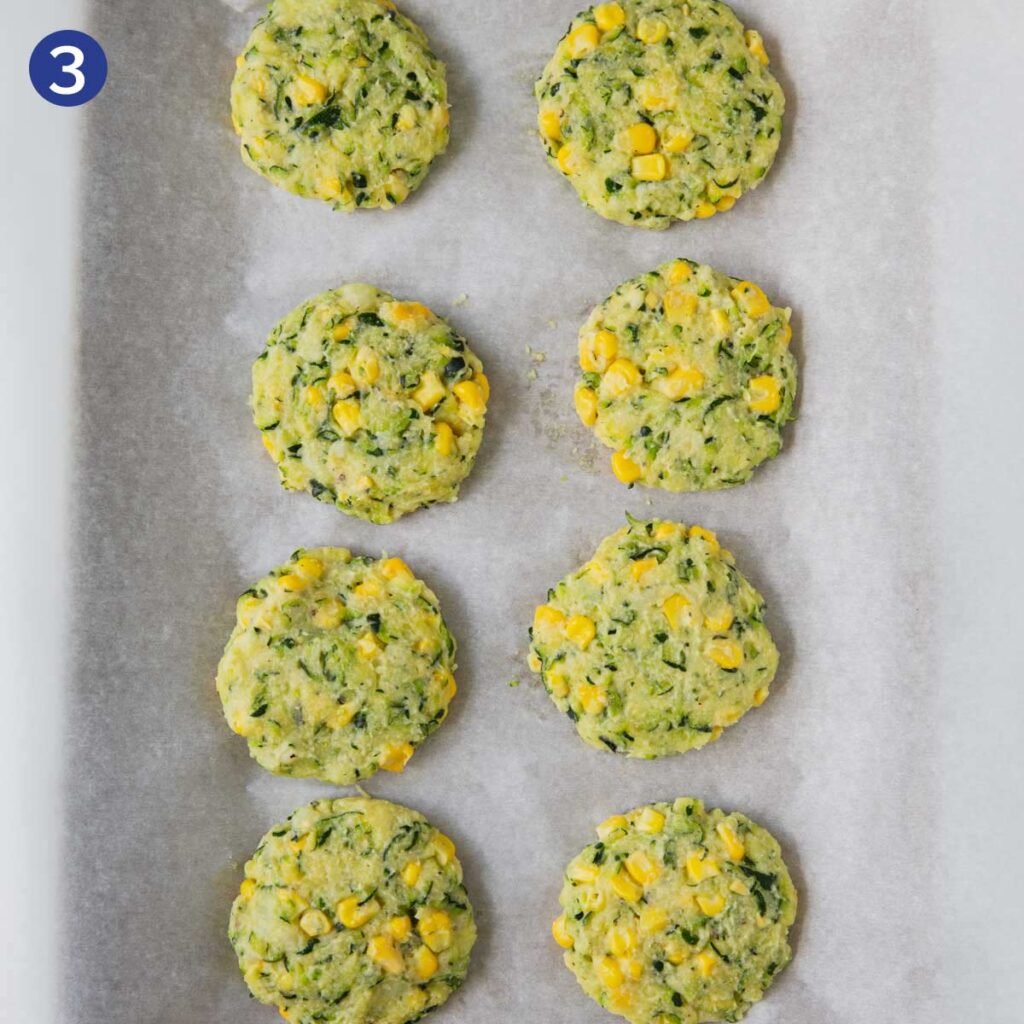 Raw zucchini corn fritters on a parchment paper. 