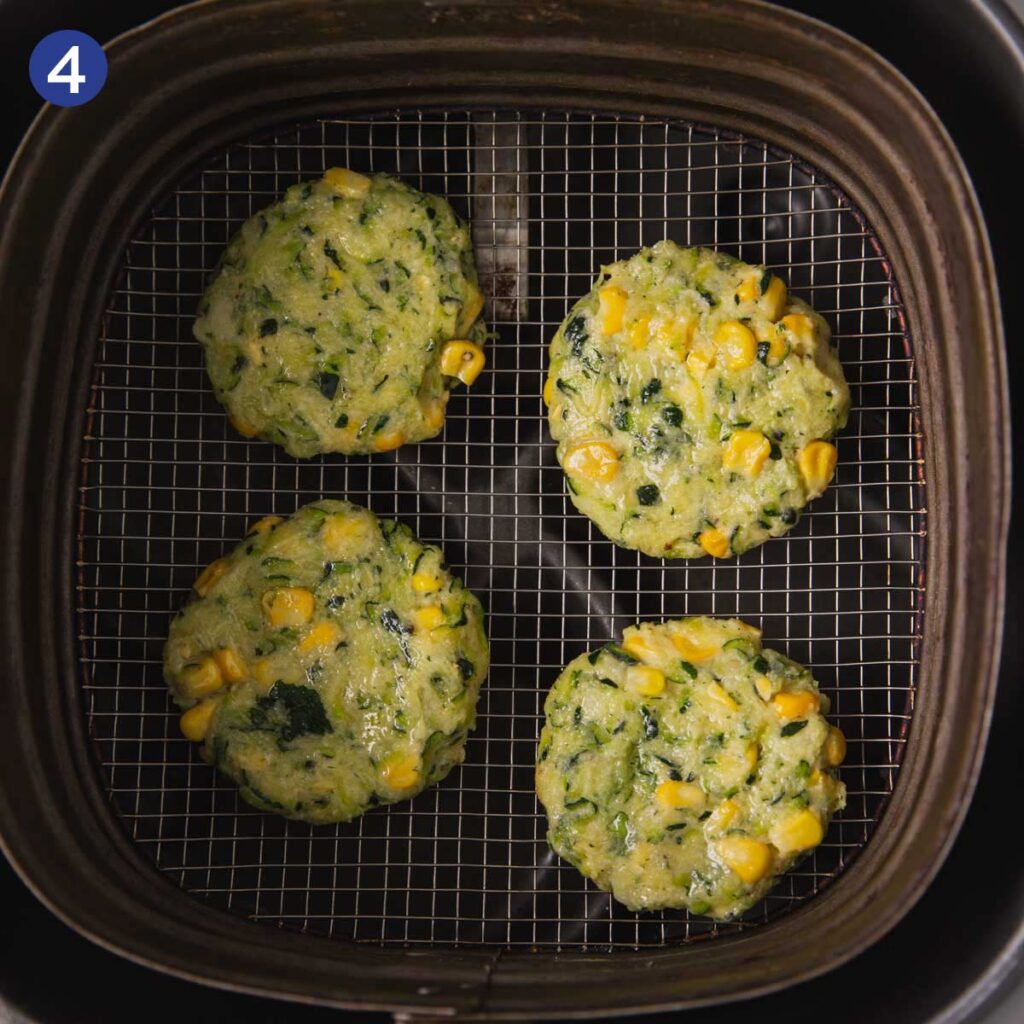 Raw zucchini corn fritters in an air fryer basket.