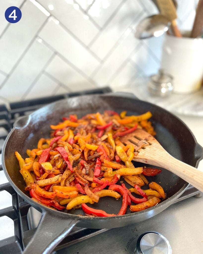 Roasting sliced peppers and onion with fajita seasonings in a cast iron pan.