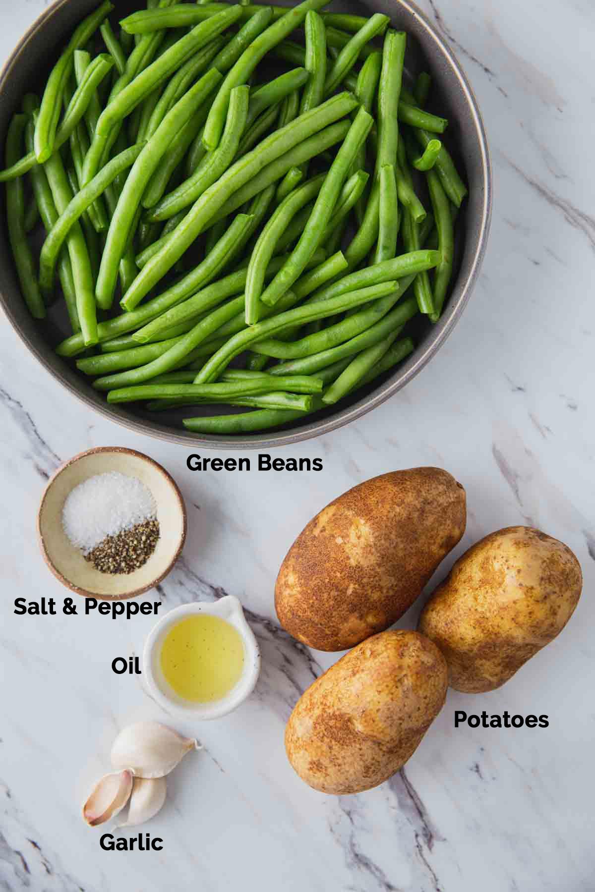 Fresh green beans, raw potatoes, oil, whole garlic cloves, salt and pepper gathered for making pan roasted green beans and potatoes. 