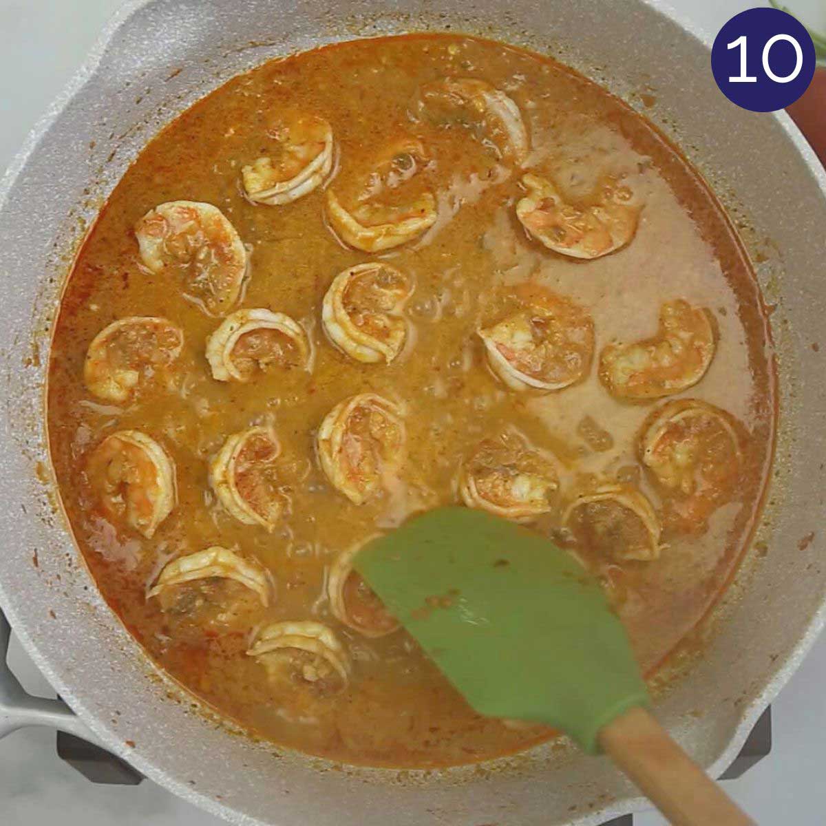 Fully cooked shrimp curry with coconut milk in a skillet is ready to serve.