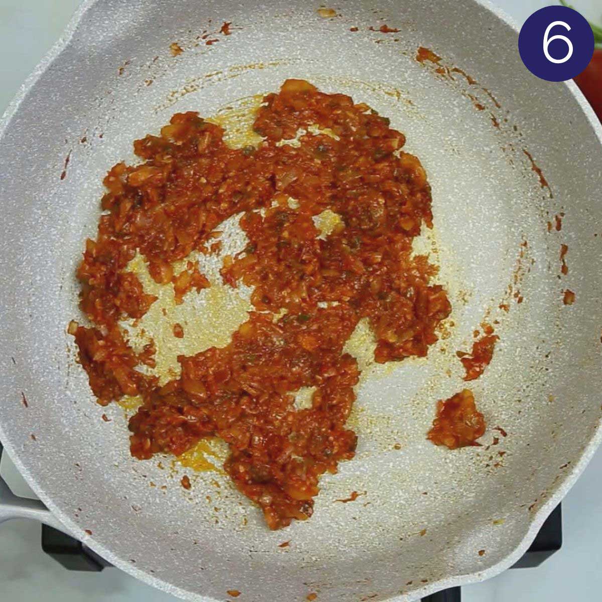 Cooked onion and tomato mixture in a skillet.