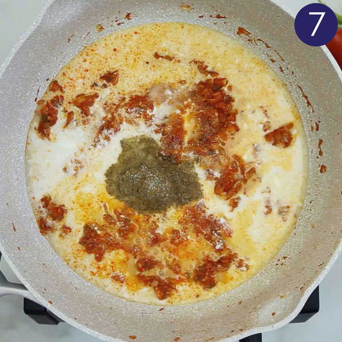 Preparing shrimp curry base with coconut milk, onion, and tomato in a skillet.