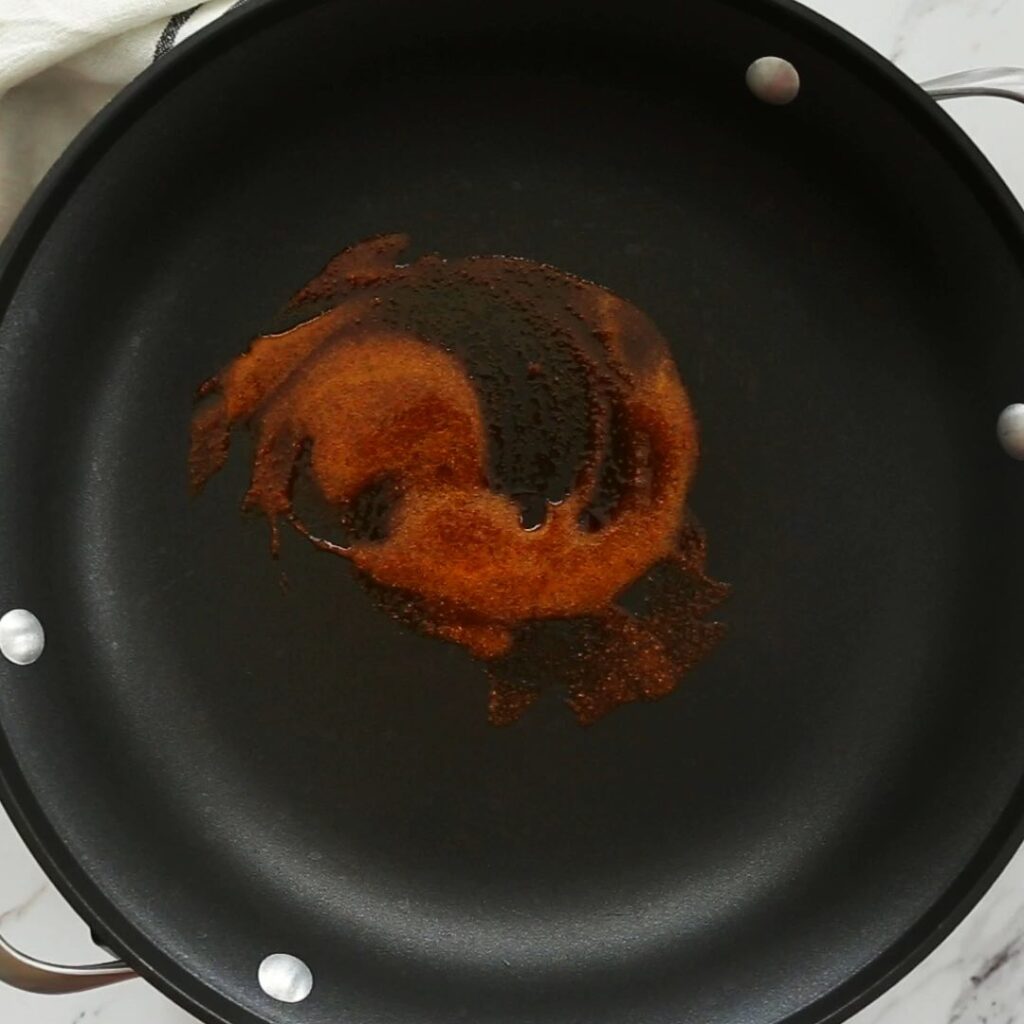 Process of frying some chili powder in oil in a skillet. 