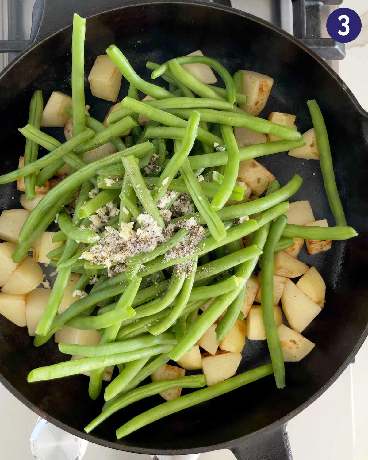 Green beans and potatoes in a cast iron pan while roasting. 