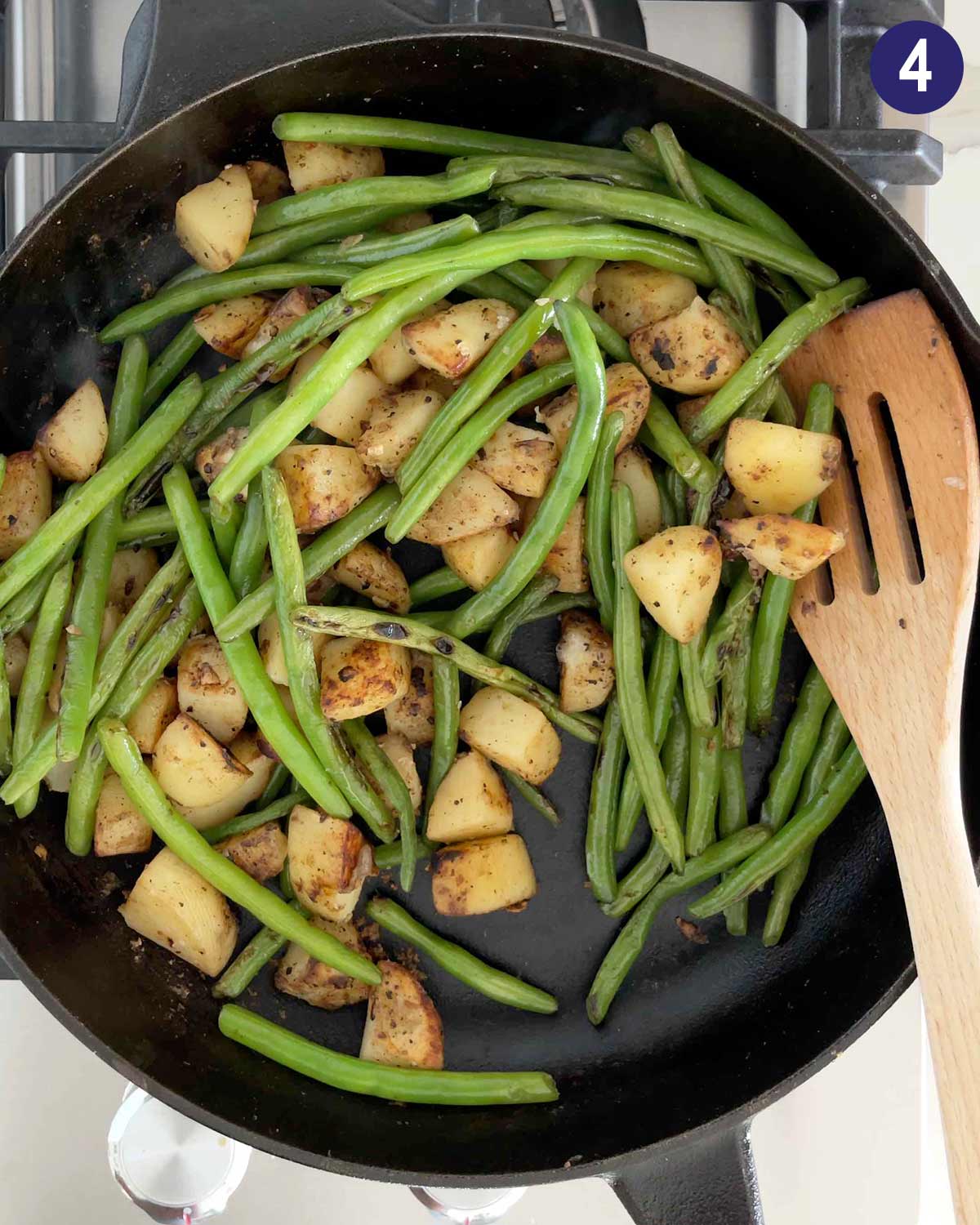 Roasted green beans and potatoes in a cast iron pan after cooking. 