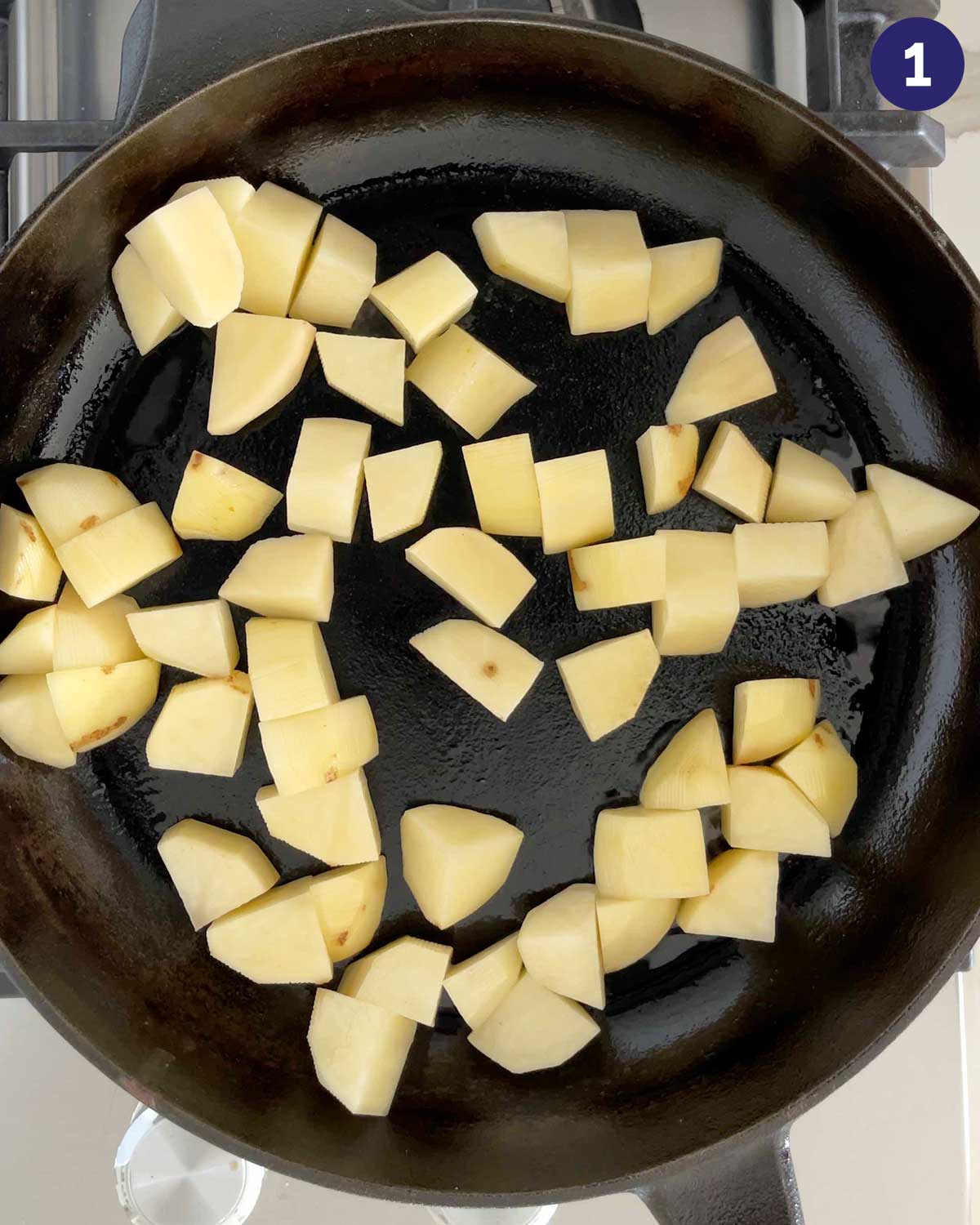 Diced potatoes in a cast iron pan at the beginning of roasting.