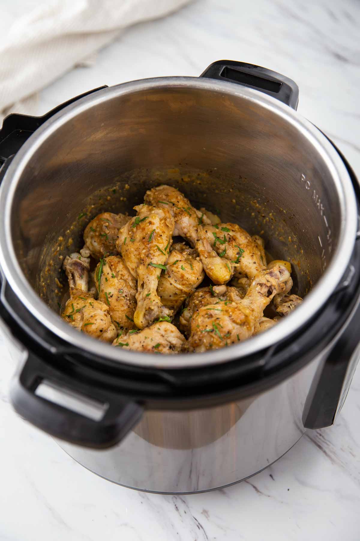 Instant Pot chicken legs with lemon garlic sauce and garnished with fresh parsley.