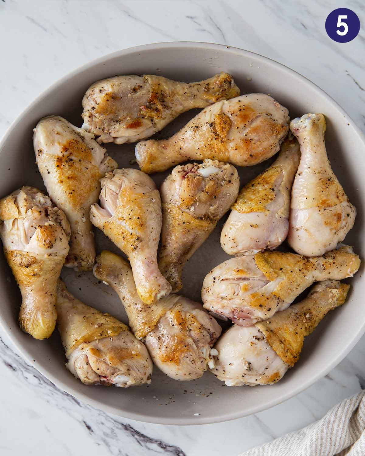 Roasted chicken drumsticks in a large shallow bowl before pressure cooking.