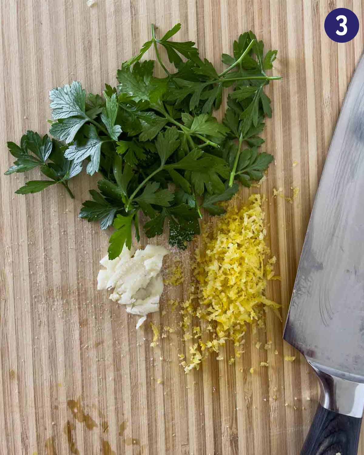 Fresh parsley, lemon zest and garlic on a cutting board to prepare gremolata.