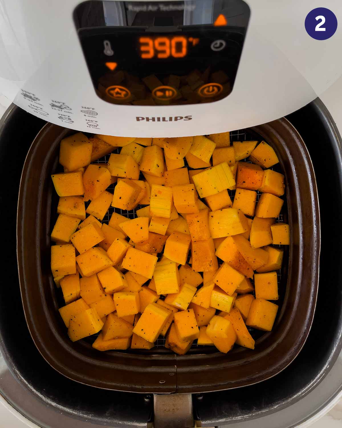 Diced butternut squash in Air Fryer basket at the beginning of cooking.