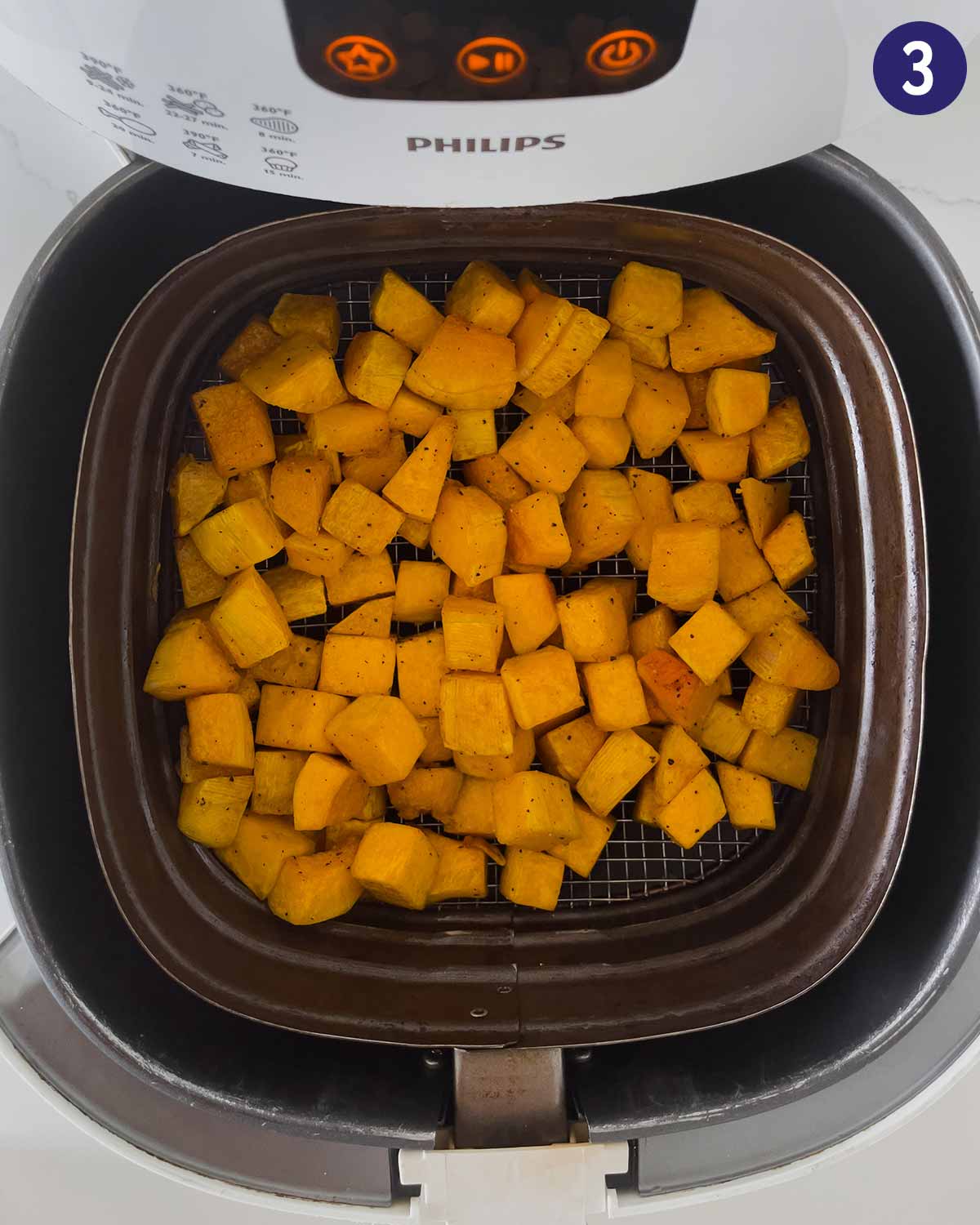 Diced butternut squash in Air Fryer basket at the beginning of cooking.