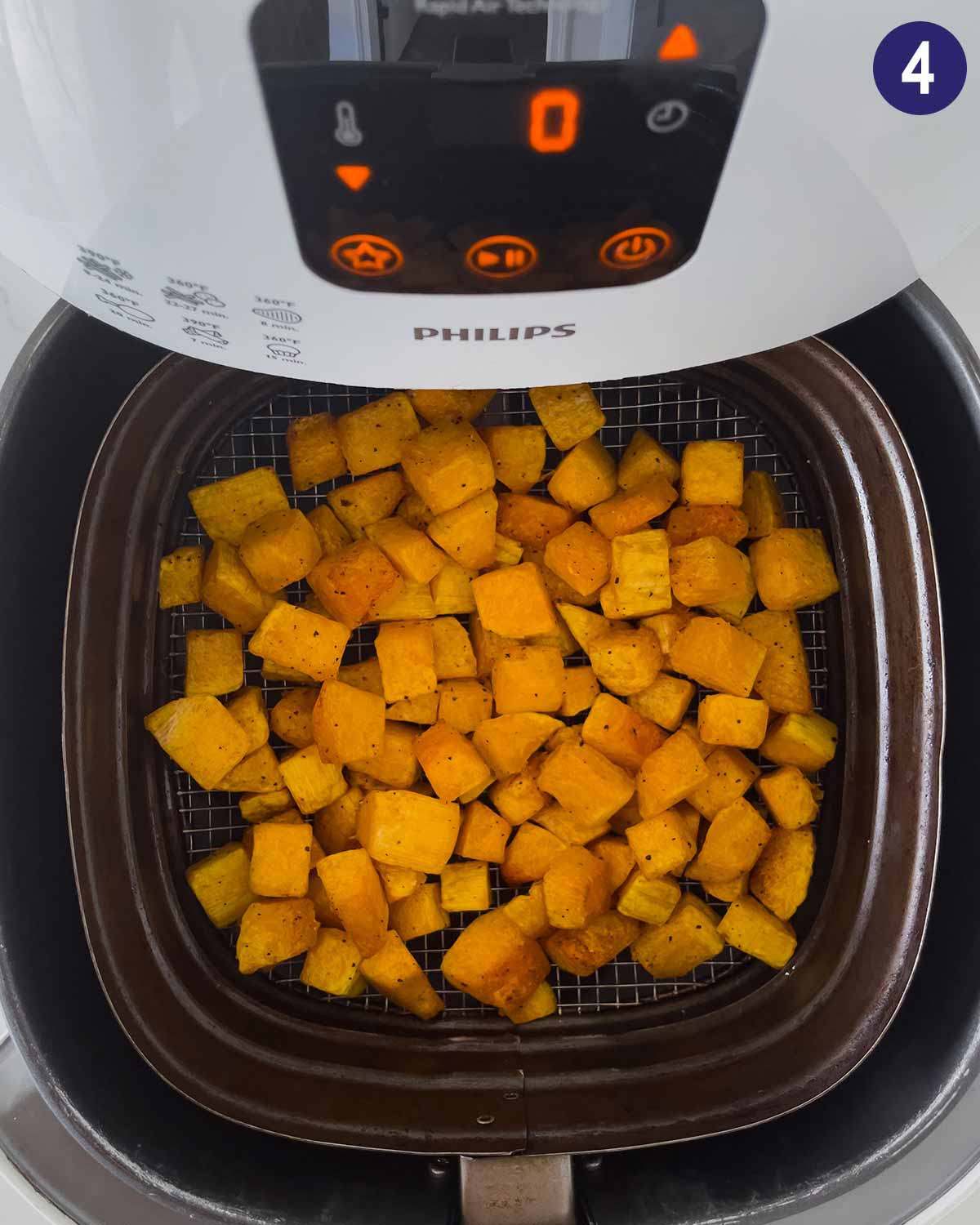 Diced butternut squash in Air Fryer basket during cooking.