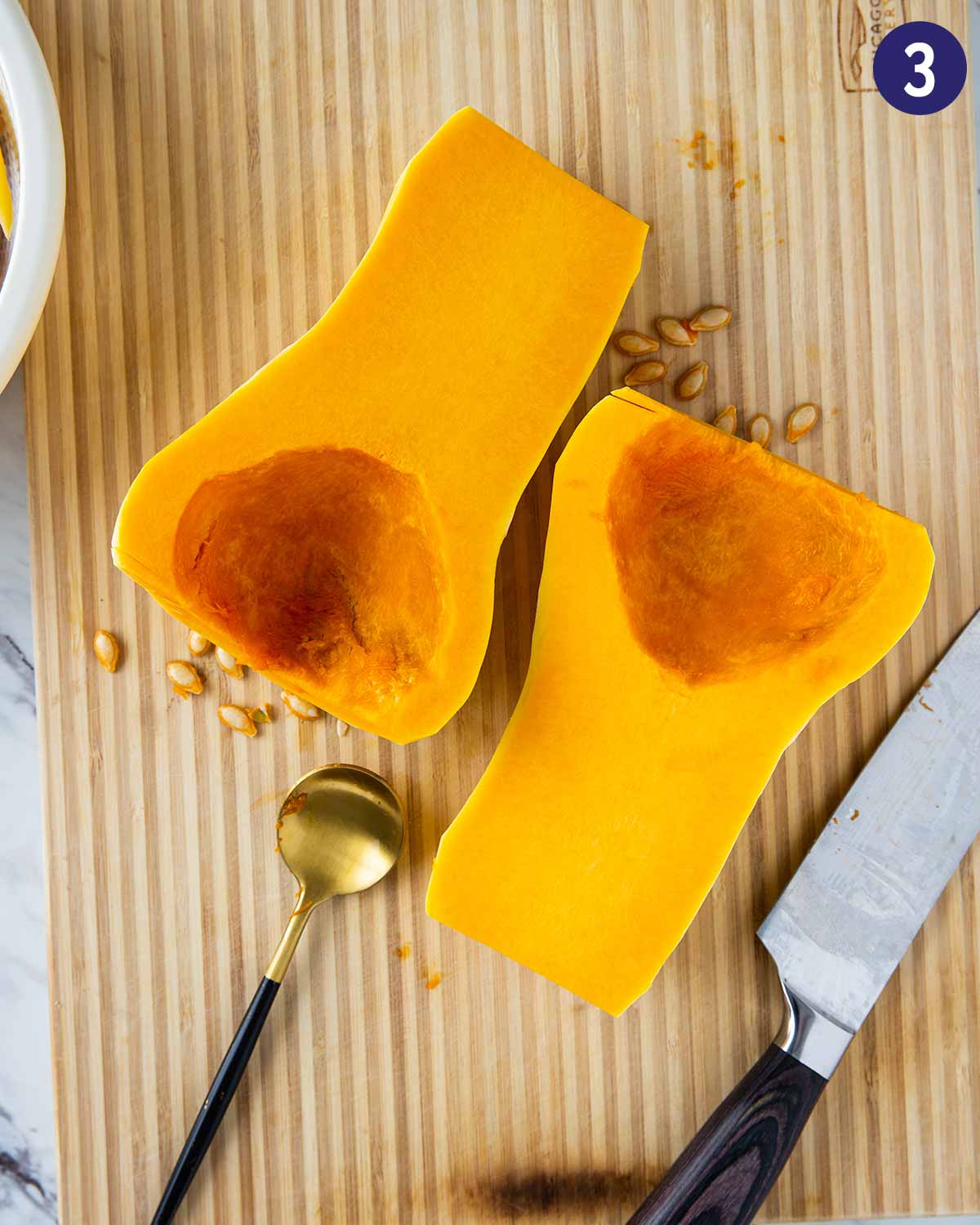 Butternut squash after peeling and removing seeds placed on the cutting board with a metal spoon and knife.