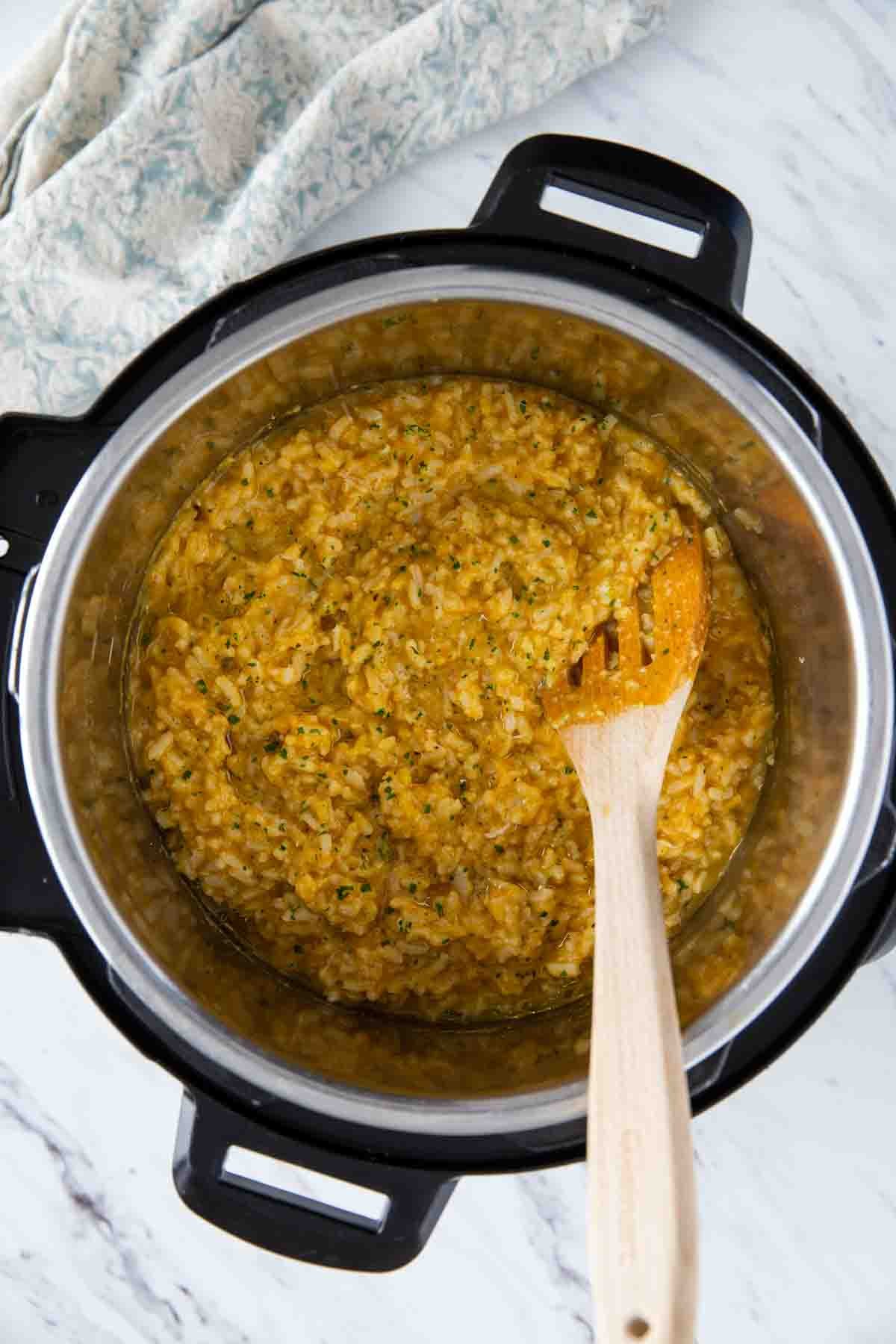 Instant Pot Pumpkin risotto with a wooden spatula.