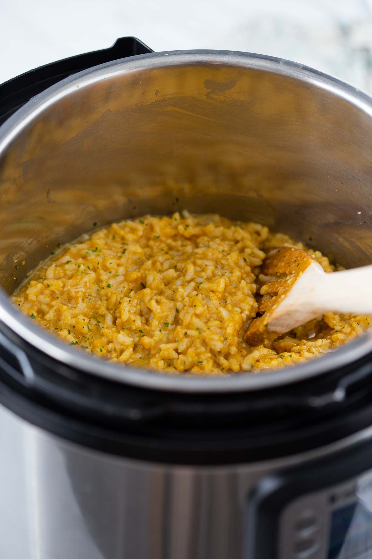 Instant Pot Pumpkin risotto with a wooden spatula.