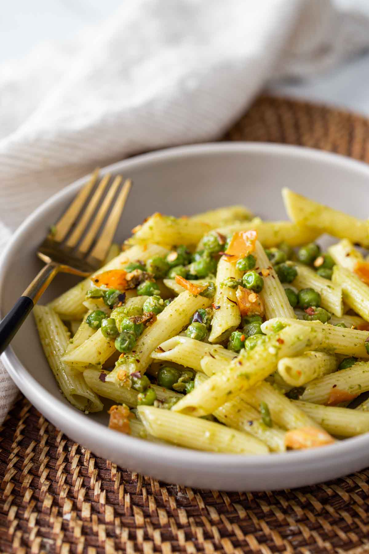 Pesto and Peas pasta in a served in a dish with a metal fork.