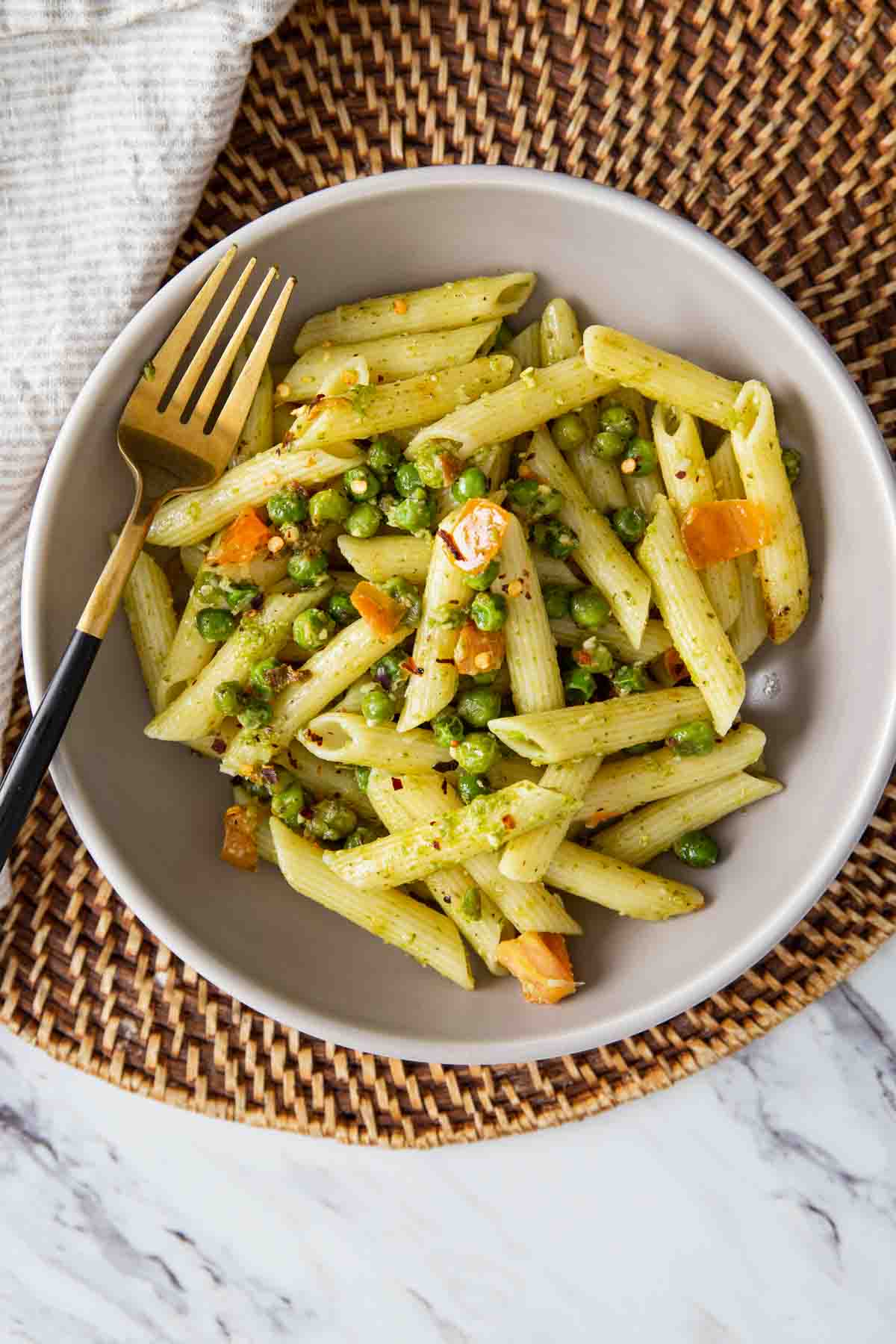 Pesto and Peas pasta in a served in a  dish with a metal fork.