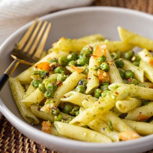 Pesto and Peas pasta in a served in a dish with a metal fork.