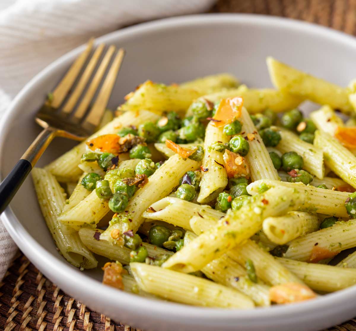 Pesto and Peas pasta in a served in a dish with a metal fork.